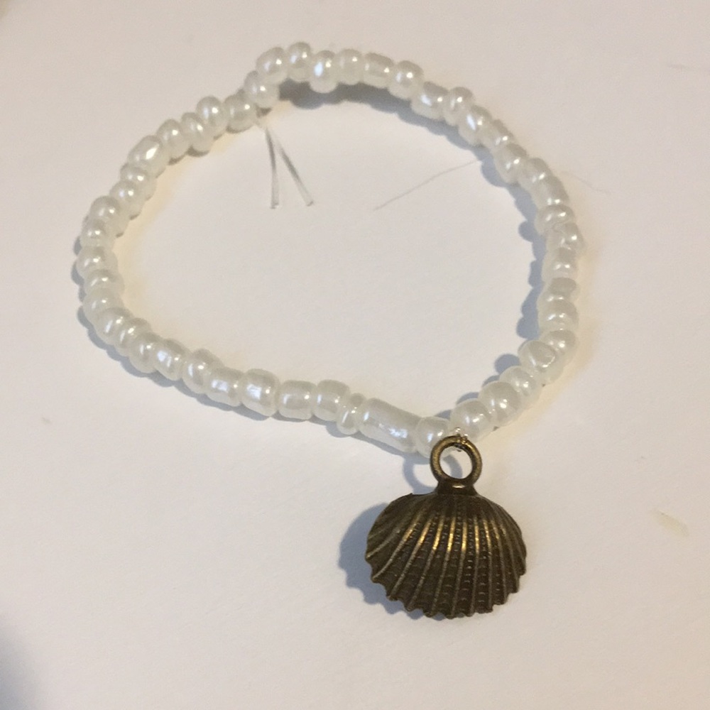 White beaded bracelet with dark brown shell charm